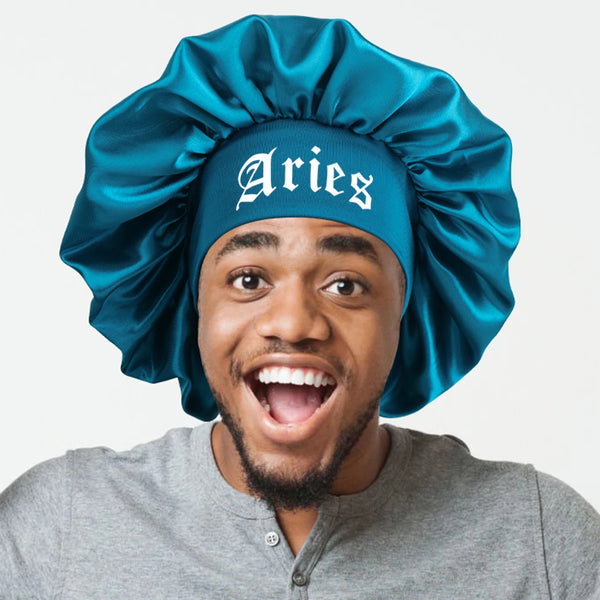 A man wearing a teal satin sleep bonnet with an Aries wrap band and a gray shirt.
