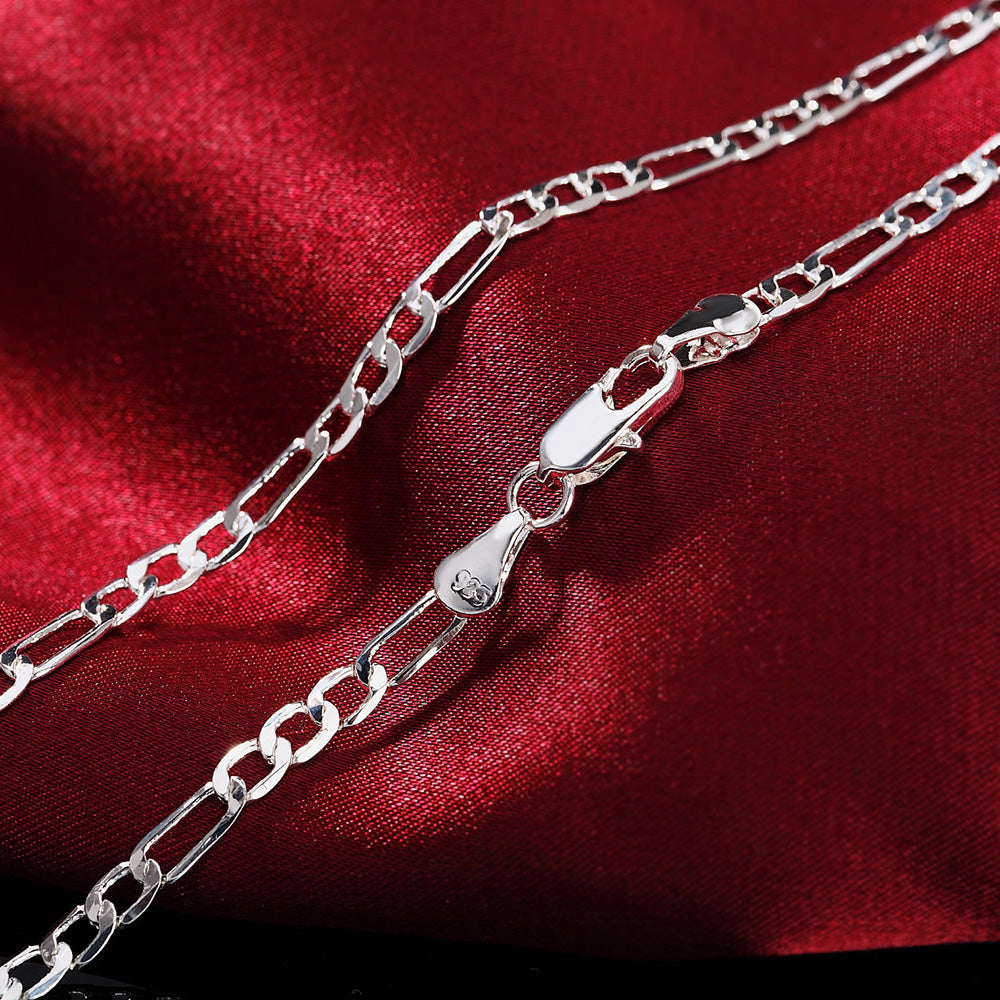 A set of sterling silver charm necklaces and bracelets displayed against a deep red velvet fabric.