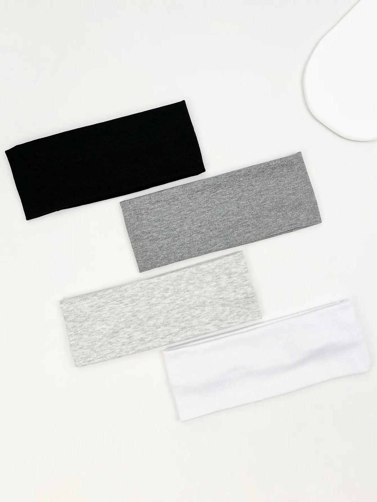 A set of four knitted hair bands in black, gray, and white are displayed on a white background.