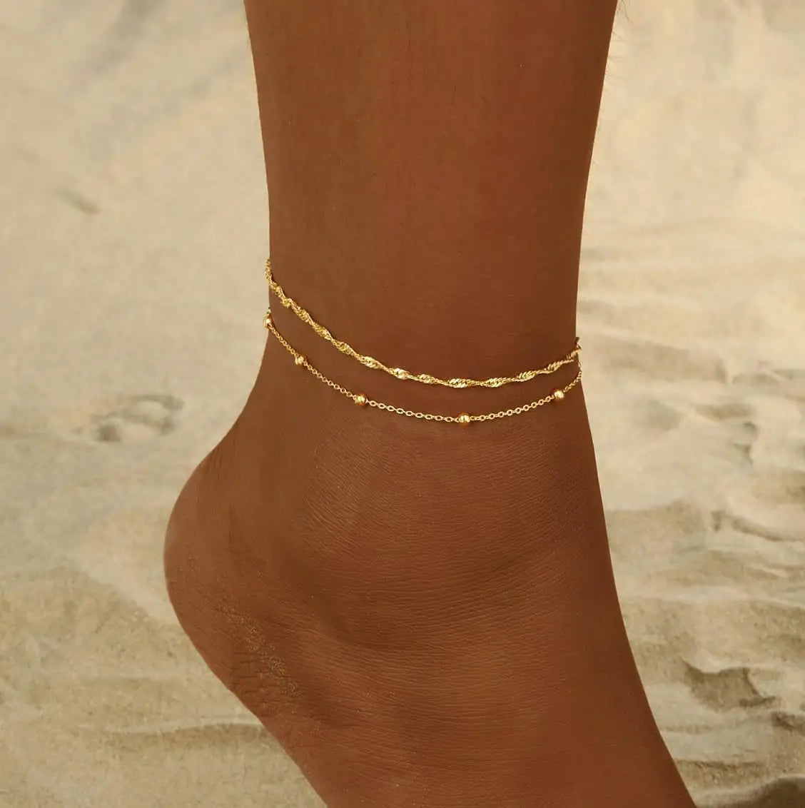 Gold plated beaded anklets worn around the ankle of a person's foot.