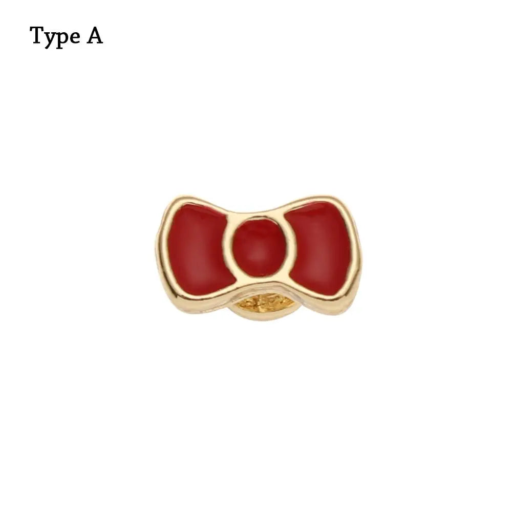 Adorno de pulsera de metal decorativo con diseño de esmalte rojo y montura dorada.