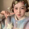 A close-up of a person with hair clips shaped like stars on their forehead, touching their face.