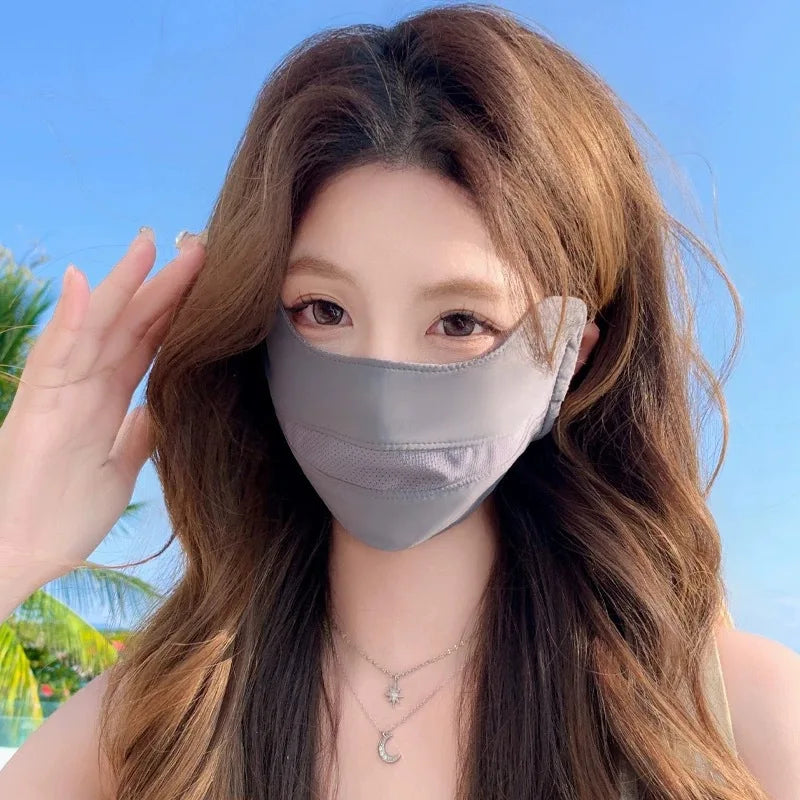 A woman models a gray breathable ice silk UV protection face mask against a bright blue sky background.