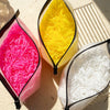 Three packets of colorful disposable rubber hair ties, including pink, yellow, and white varieties.