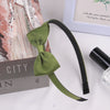 A green grosgrain ribbon hair bow is displayed next to a box and a framed picture.