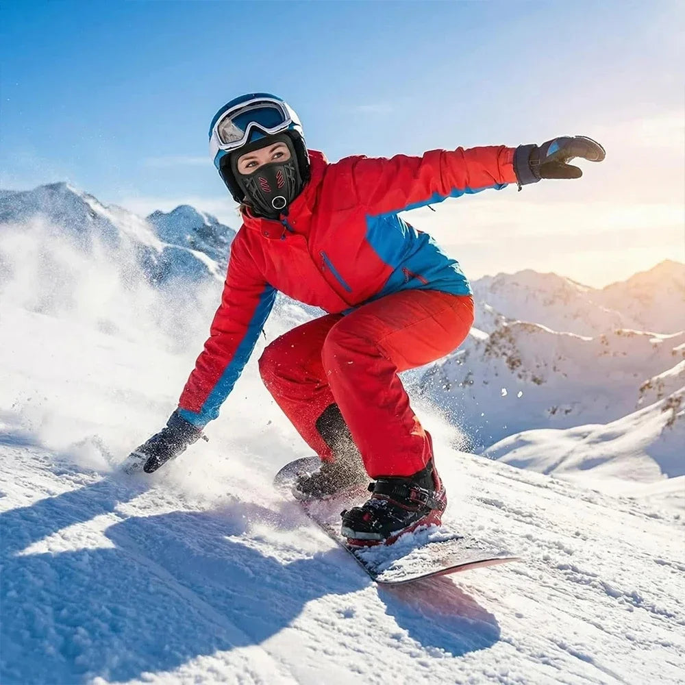 A woman wearing a red and blue winter sports jacket is snowboarding down a snowy slope with powder flying.