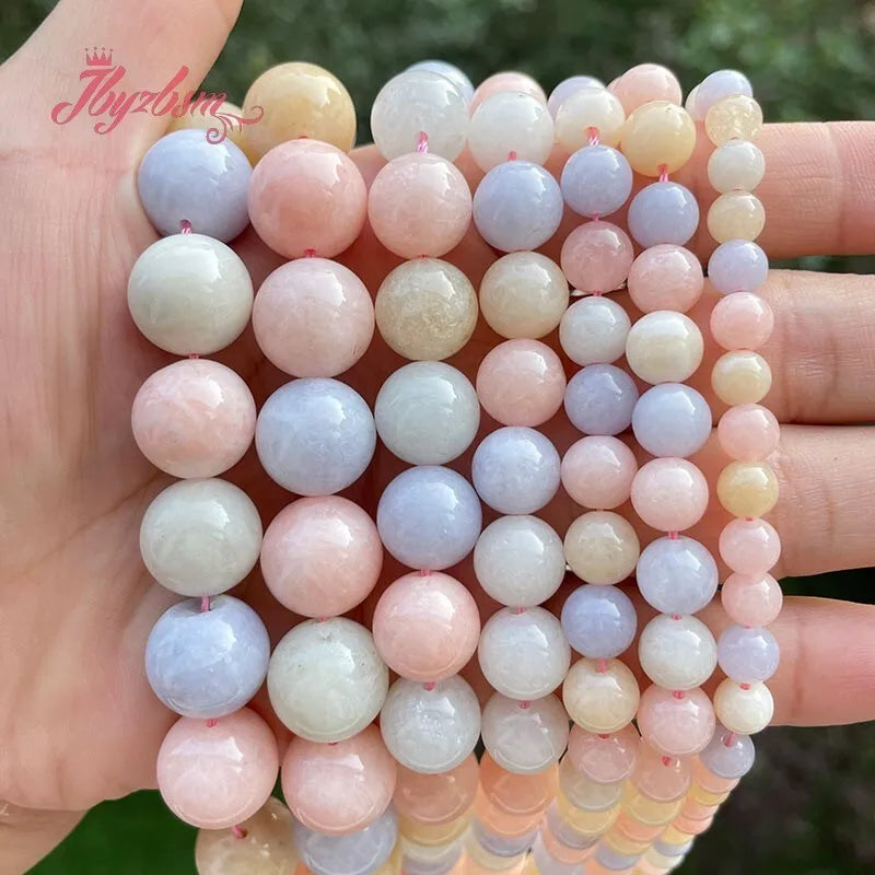 A hand holds a string of smooth round jade beads in various pastel colors for DIY jewelry making