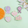A set of enamel pins featuring funny quotes and awards on a light green background.