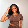 Femme modélisant une perruque tressée cornrows naturelle de 16 pouces avec un haut et un bas assortis marron.