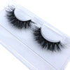 A pair of natural mink false eyelashes displayed in a clear plastic container.