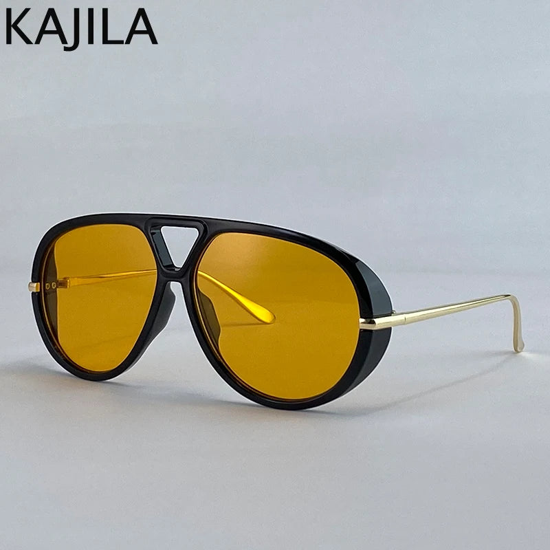 Gafas de piloto vintage oversize con montura negra y lentes ámbar sobre fondo blanco.