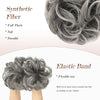 A close-up of gray synthetic fiber hair pieces and an elastic band for creating a messy bun hairstyle.