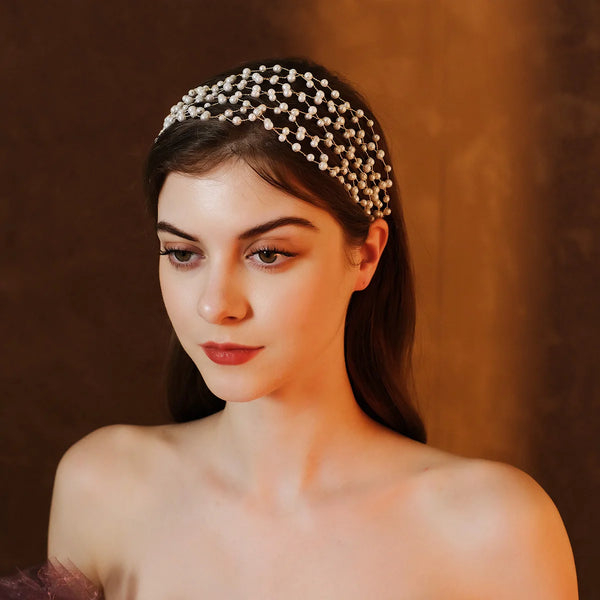 A close-up of a woman wearing an elegant pearl hair net headband against a warm brown background.