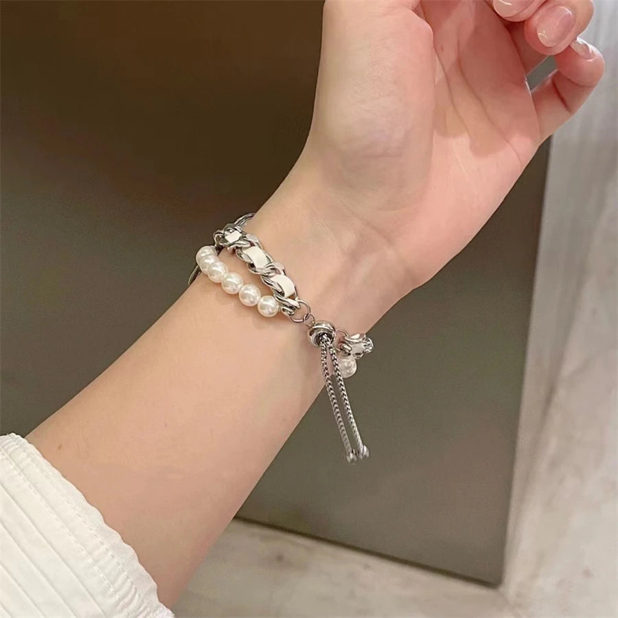 A hand is wearing a silver beaded watch strap with pearl accents on a wrist.