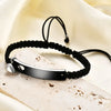 Schwarzes Perlenarmband mit silbernem Anhänger und passender Edelstahlmanschette auf hellem Stoff