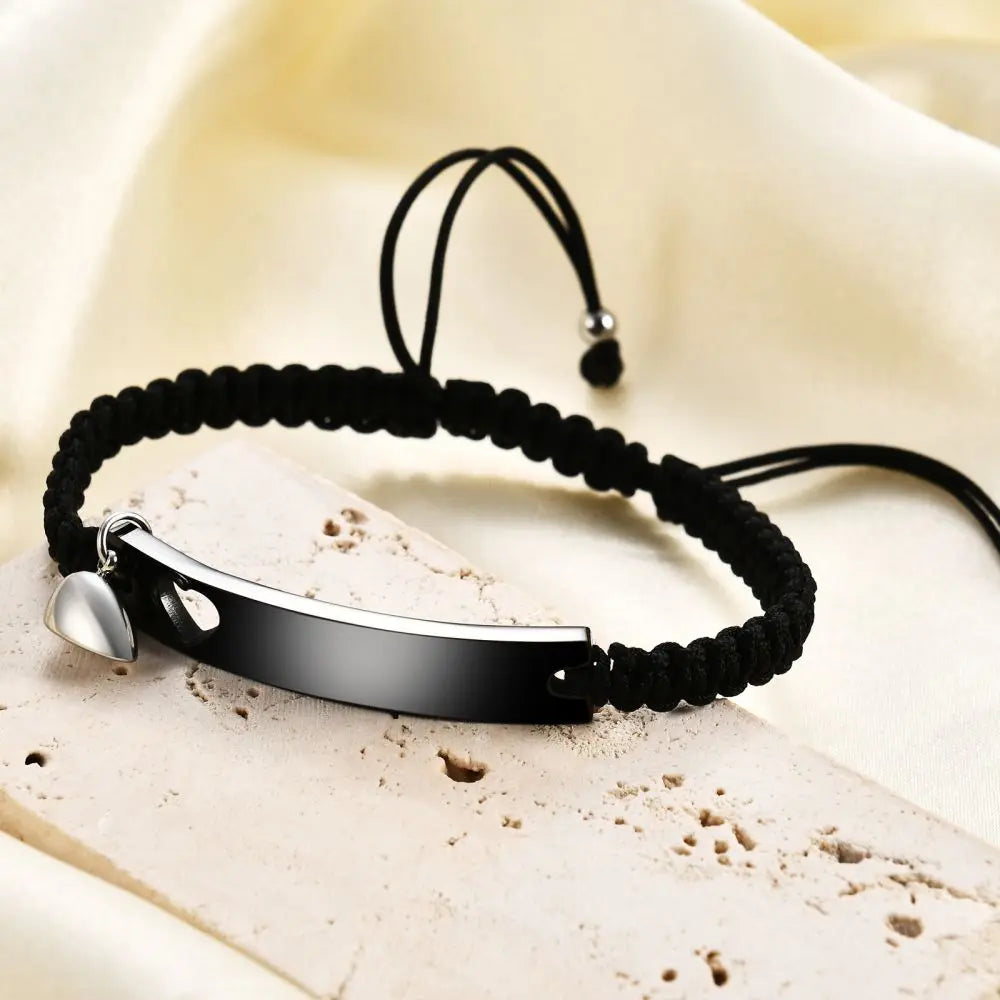 Schwarzes Perlenarmband mit silbernem Anhänger und passender Edelstahlmanschette auf hellem Stoff