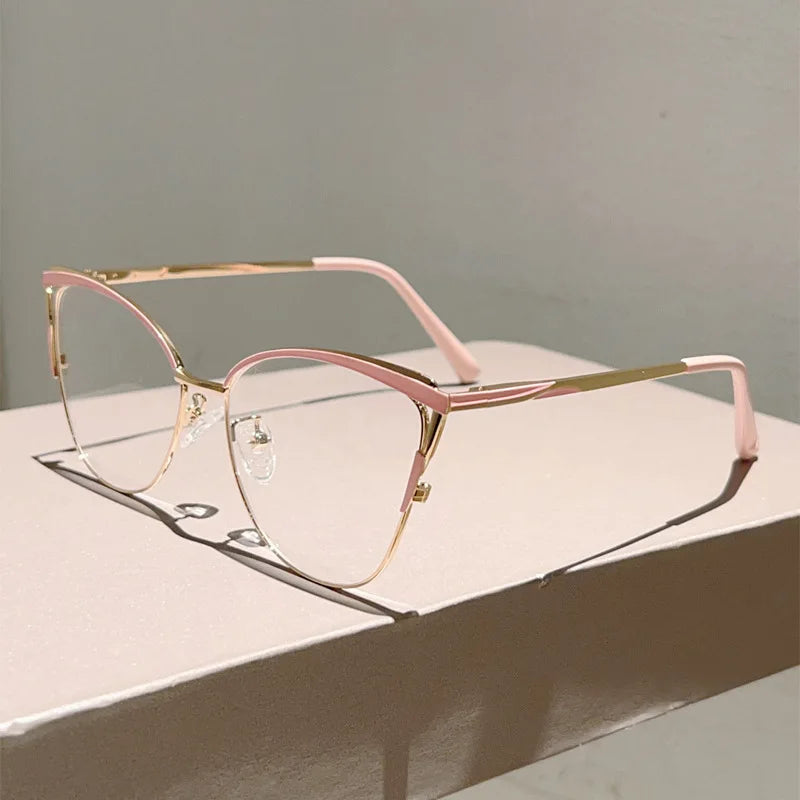 Un par de gafas de computadora con ojo de gato de metal rosa y dorado sobre una superficie clara.