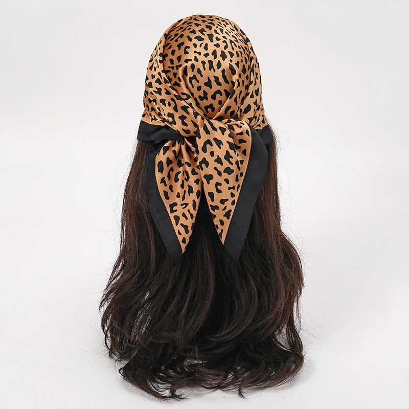 Schwarzer Satin-Schal mit Leopardenmuster, um die dunklen Haare gebunden.