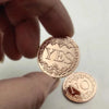 A hand holds two vintage antique bronze decision coins, one engraved with YES and the other with NO.
