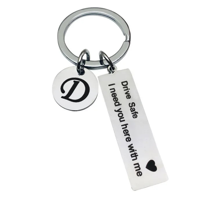 Silver keychain with a D initial charm and the text Drive Safe I need you here with me