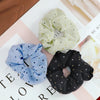 A set of three light green polka dot fabric scrunchie headbands displayed on a white surface.