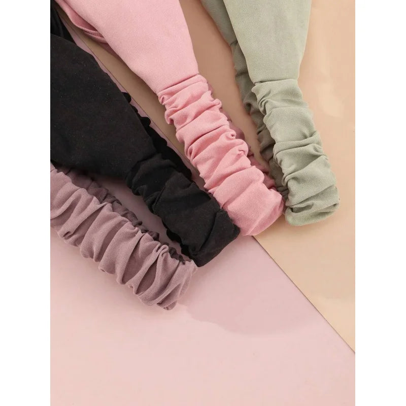 Ein Set von vier weichen Stoff-Haarbändern in Rosa, Mauve, Schwarz und Salbeigrün.