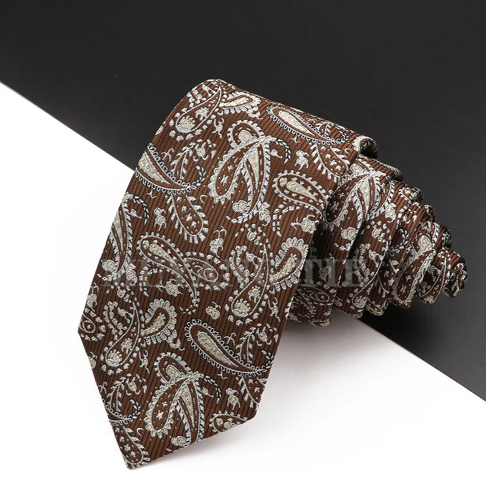 Nahaufnahme einer braun-weißen, gemusterten, luxuriösen Herrenkrawatte mit Paisley-Muster vor dunklem Hintergrund.