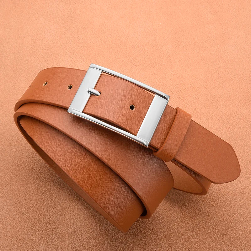 A brown leather belt with a silver metal pin buckle lying on a tan background.
