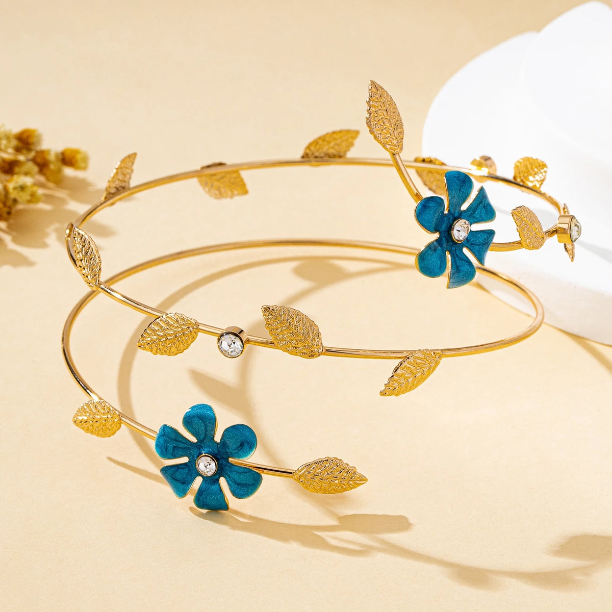 Gold and blue floral vine arm bracelets displayed on a light background.
