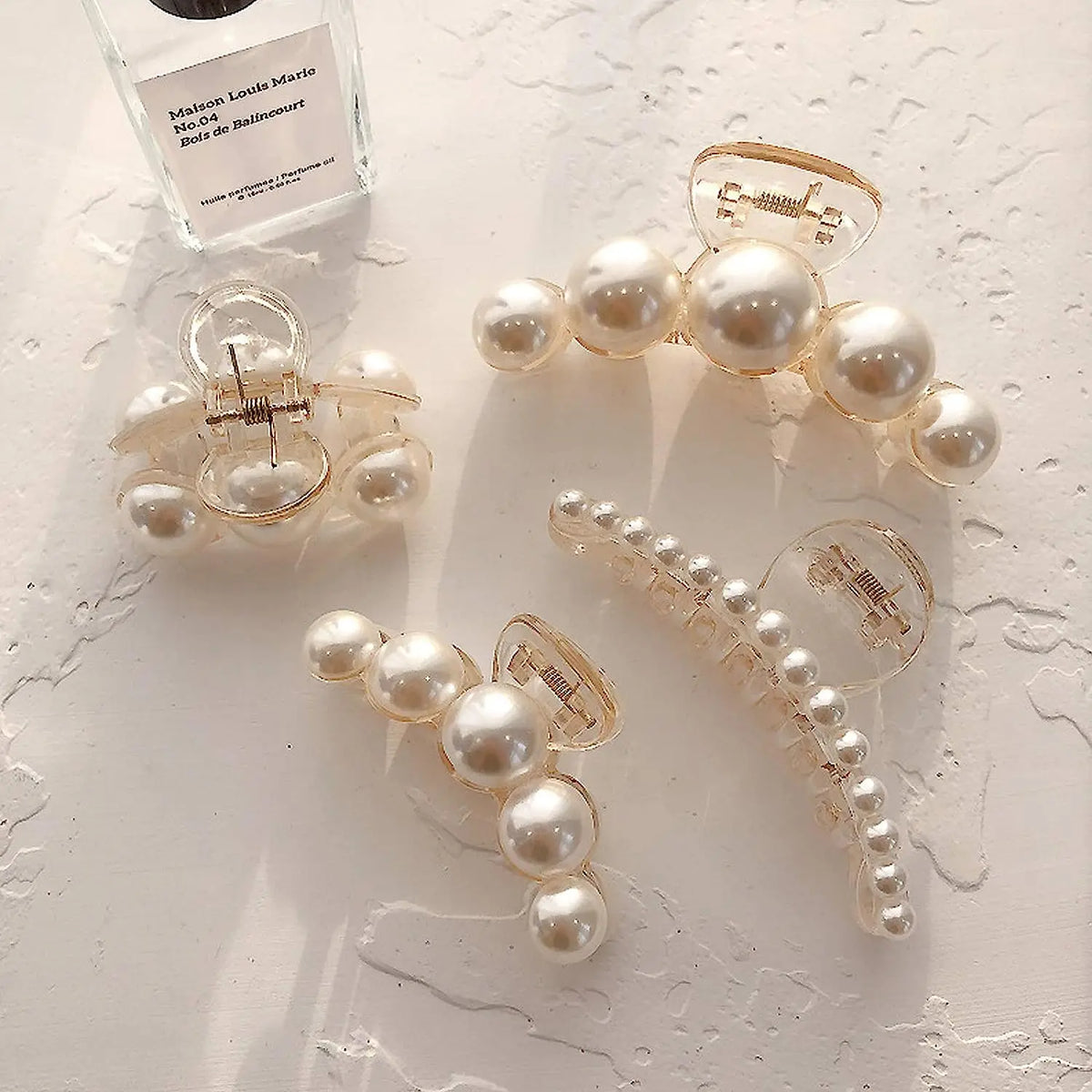 A set of simulated pearl hair claws with gold accents displayed on a white surface.