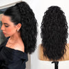 Une femme montre des extensions de cheveux noirs longs et volumineux bouclés en cours de coiffure.