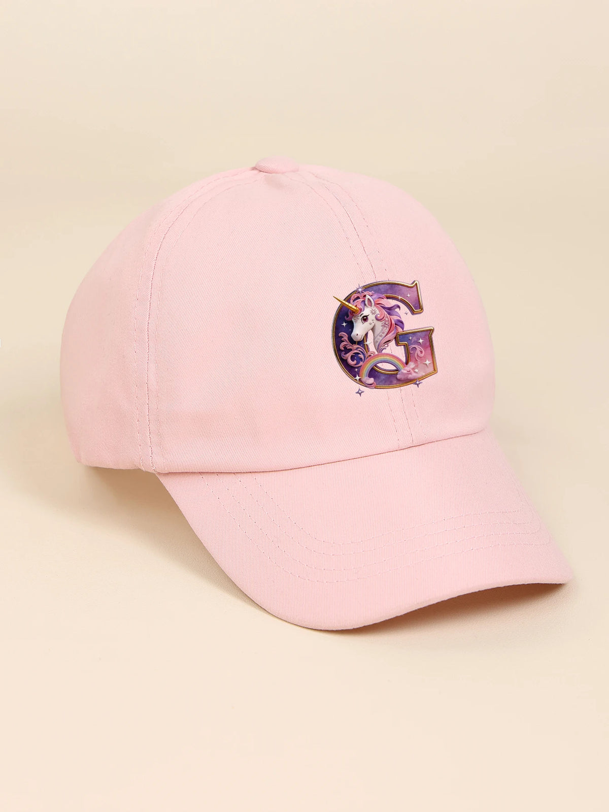 A pink baseball cap featuring a purple unicorn letter G embroidered on the front.