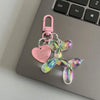 A pink and iridescent resin animal dog keychain hanging from a metal clasp on a silver laptop.