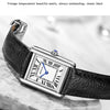 Nahaufnahme einer schwarzen Lederarmbanduhr mit silbernem Gehäuse und blauem Zifferblatt auf Marmor.