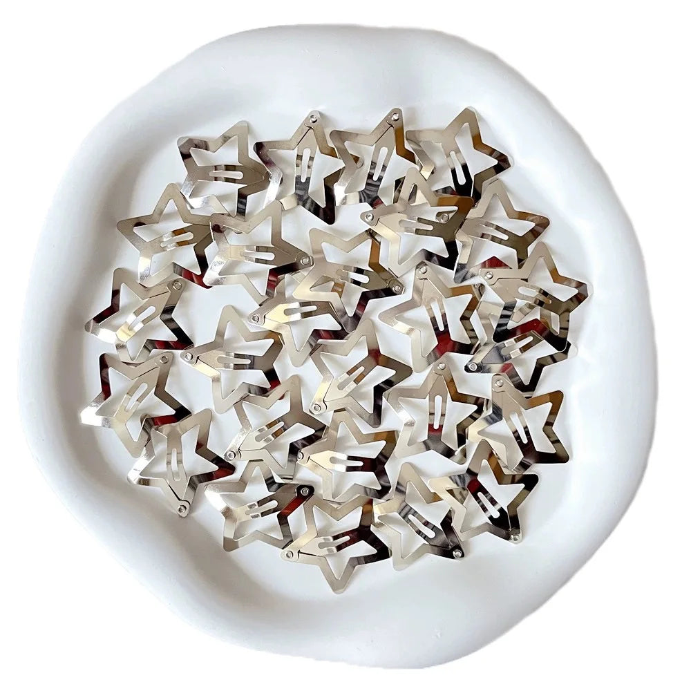 Una colección de pinzas para el cabello en forma de estrella plateada, dispuestas en un plato blanco.