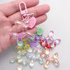 A hand holds a collection of pink and clear resin animal dog keychains.