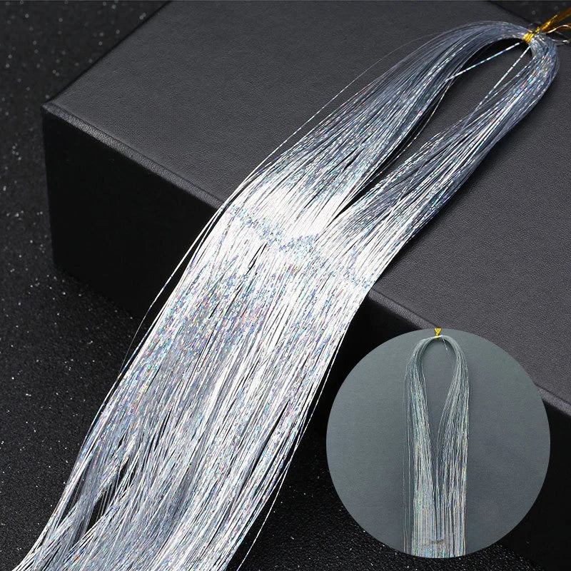 A bundle of silver glitter hair extensions for braiding laid across a dark surface.