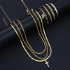 A collection of gold-toned stainless steel chains and cross necklaces displayed on a dark background.