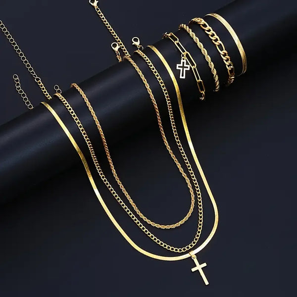 A collection of gold-toned stainless steel chains and cross necklaces displayed on a dark background.