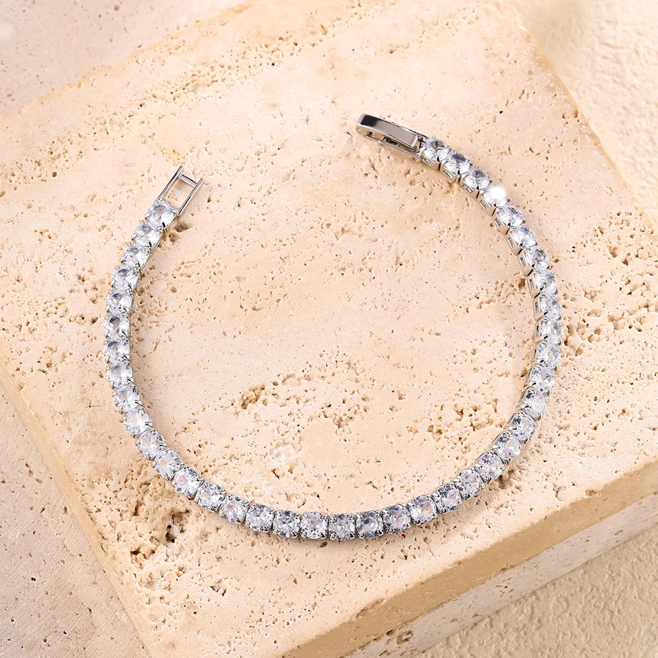 A silver bracelet set featuring a geometric design with clear rhinestones stacked together, displayed on a light beige surfac