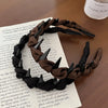 A close-up of a black knotted hair headband with teeth resting on a piece of paper.