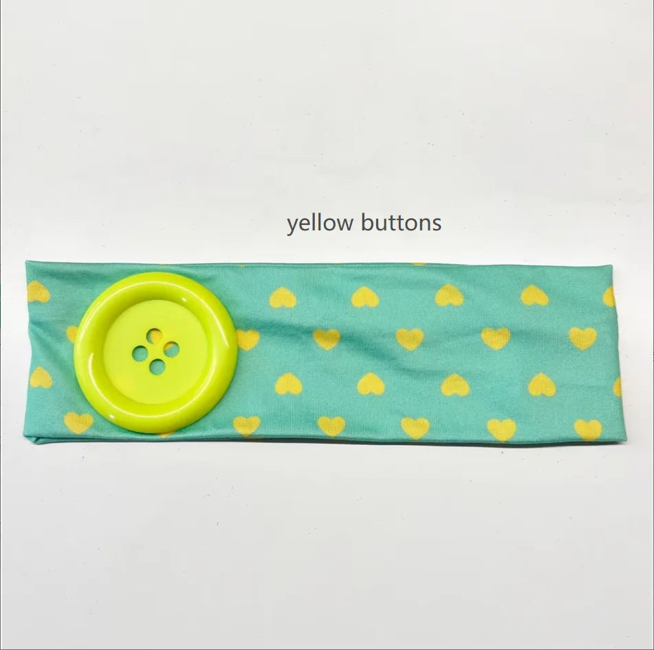 A teal headband decorated with yellow heart shapes and featuring a large yellow button.