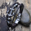 A dark brown leather bracelet featuring a silver pirate compass charm and metal accents.