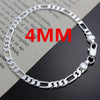 A silver charm necklace and bracelet set displayed on a piece of paper.