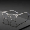 Lunettes vintage à demi-monture claires posées sur une surface sombre avec un reflet.