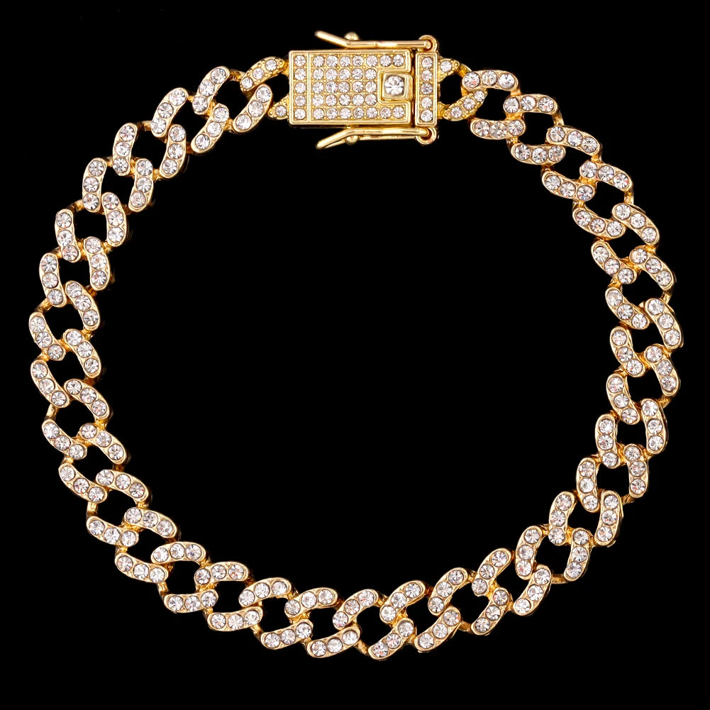 A gold crystal Cuban link anklet with a rectangular clasp is displayed against a black background.