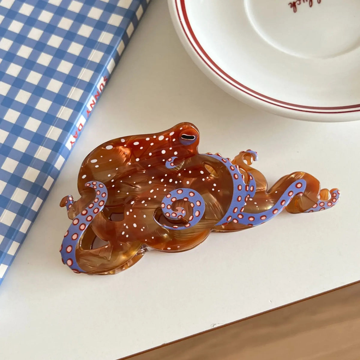 Pince à cheveux en forme d'octopus ambré brillant avec des pois violets et blancs.