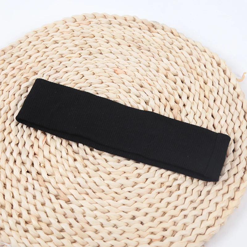 Black knitted elastic headband lying on a natural woven mat.