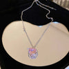 A delicate silver chain necklace featuring a pink heart-shaped zircon pendant displayed on a light background.