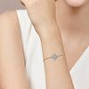 Nahaufnahme eines silbernen Hexenknoten-Zirkonia-Armbandes am Handgelenk.